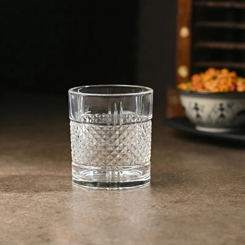 Single empty clear whiskey glass with textured geometric detailing