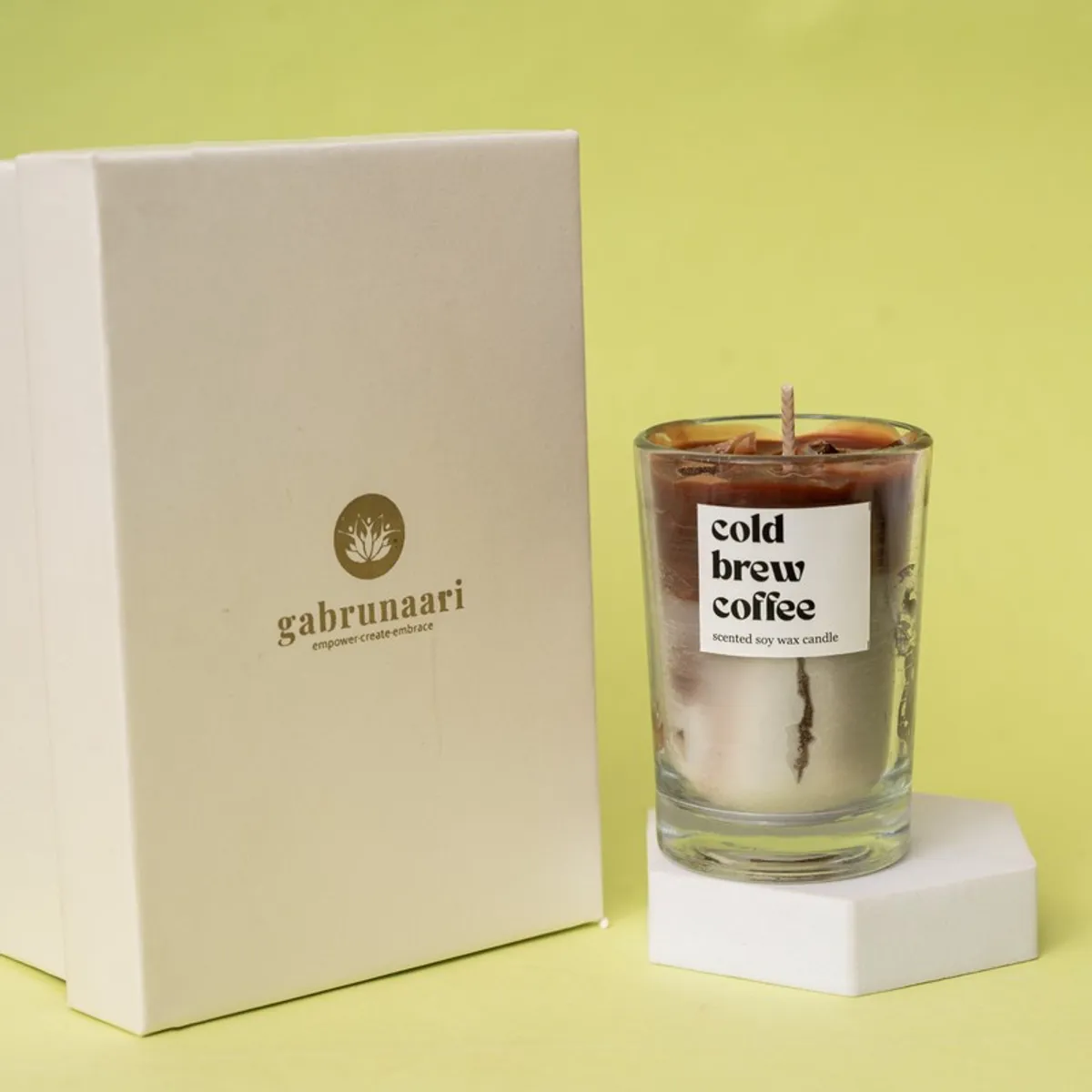 Brown coffee candle in a clear glass jar beside its cream presentation box