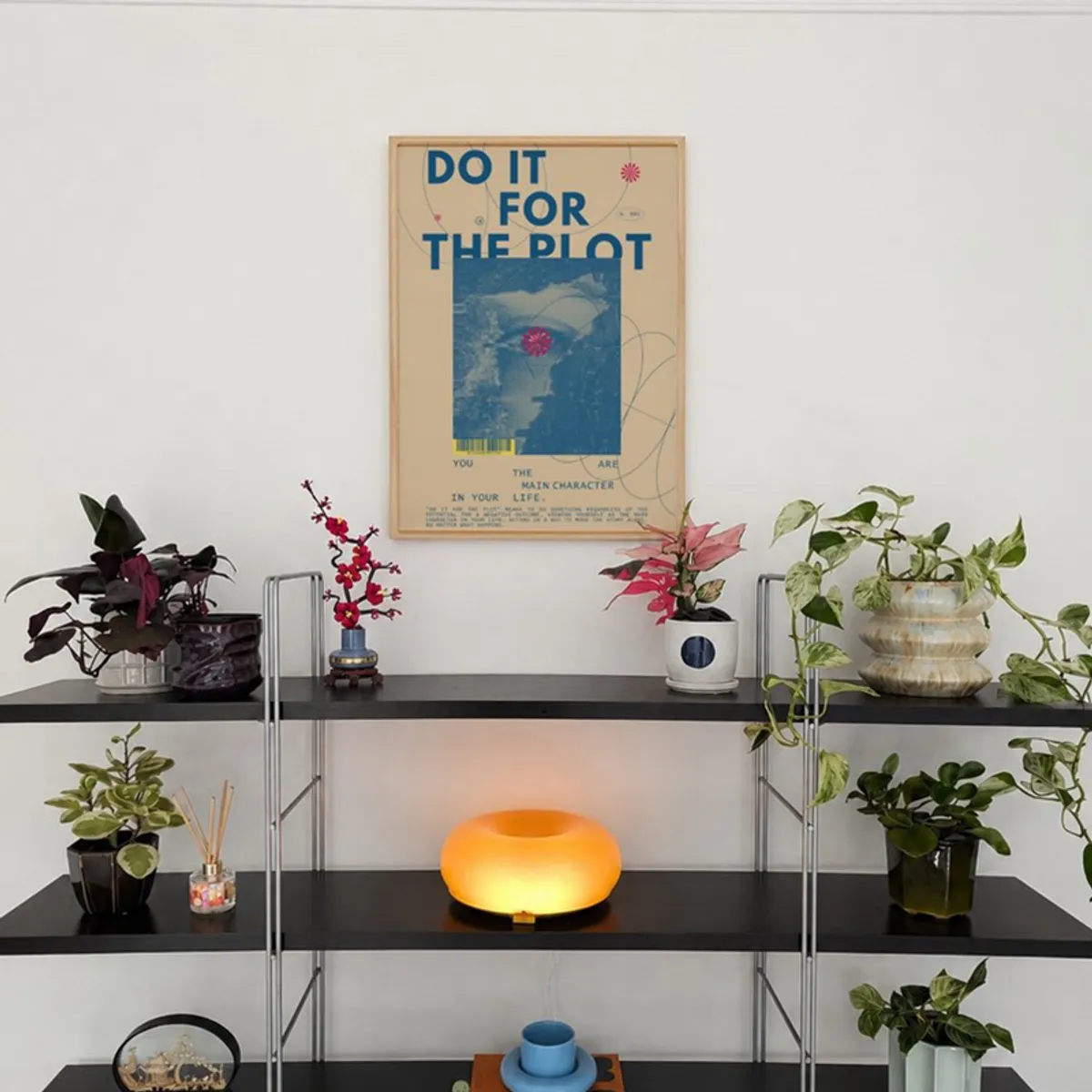Framed blue and beige wall art displayed above a plant shelf
