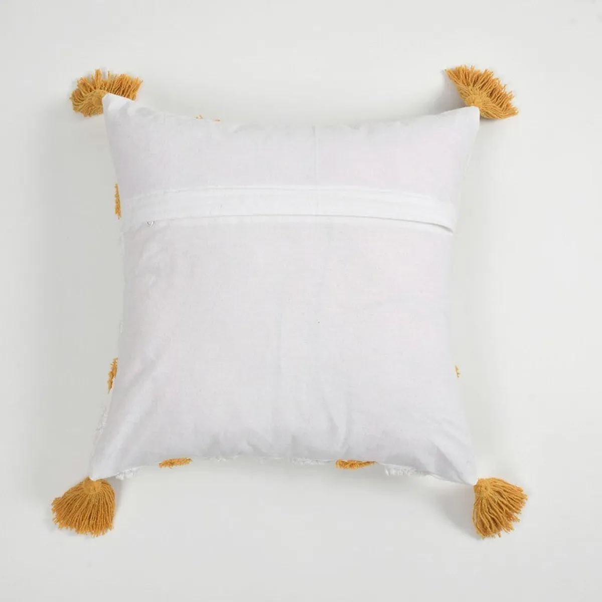 Back view of the white cushion cover showing its zip closure and yellow corner tassels