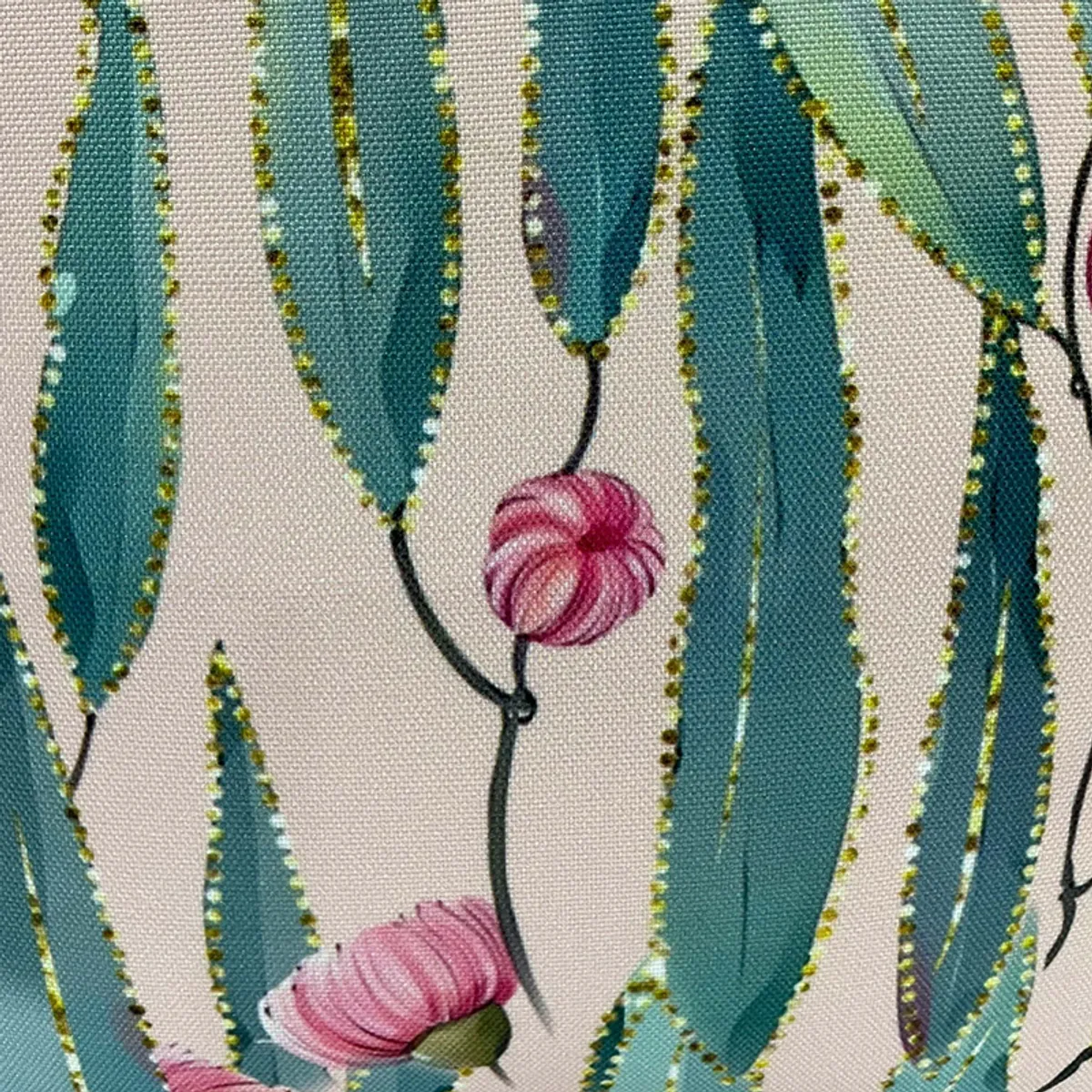 Close-up of teal leaves, pink flowers and dotted accents on a printed cushion cover