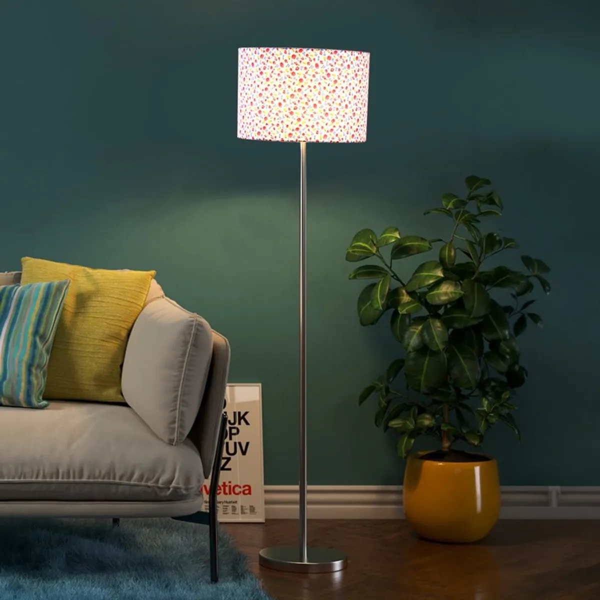 Lit multicolour drum-shade floor lamp beside a sofa and potted plant against a dark teal wall