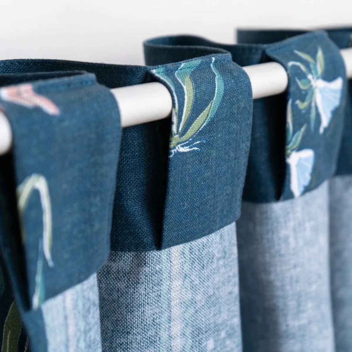 Close-up of blue curtain fabric with a pale floral motif and border stripe