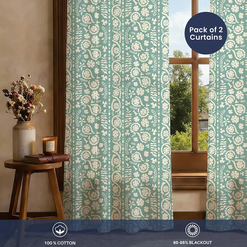 Green floral printed curtains covering a window in a styled room