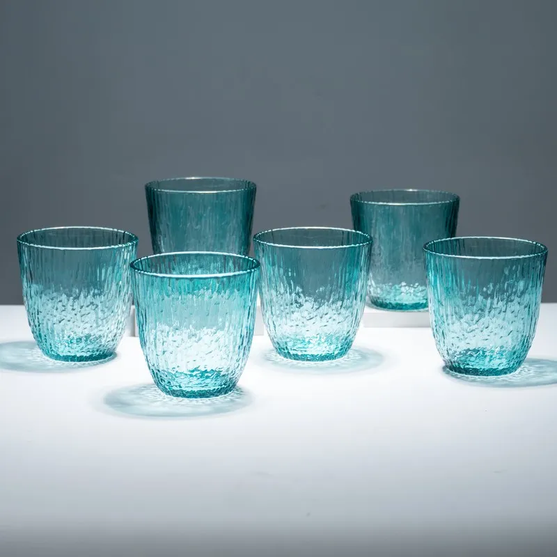 Six blue tinted textured glasses grouped on a white tabletop