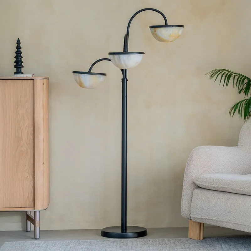 Triple-arm floor lamp with marbled semi-sphere shades beside an armchair