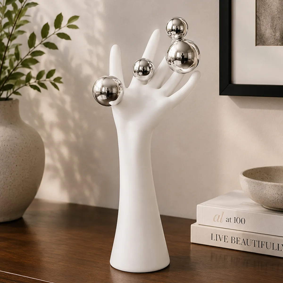 Close view of a white hand-shaped sculpture with reflective silver spheres