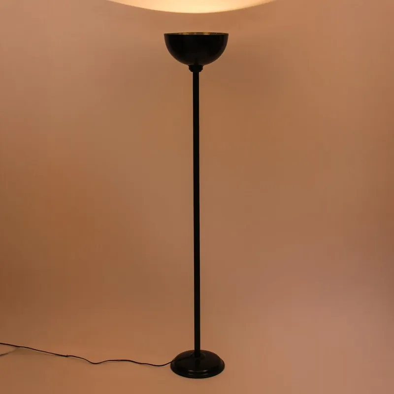 Black floor lamp glowing against a plain beige backdrop