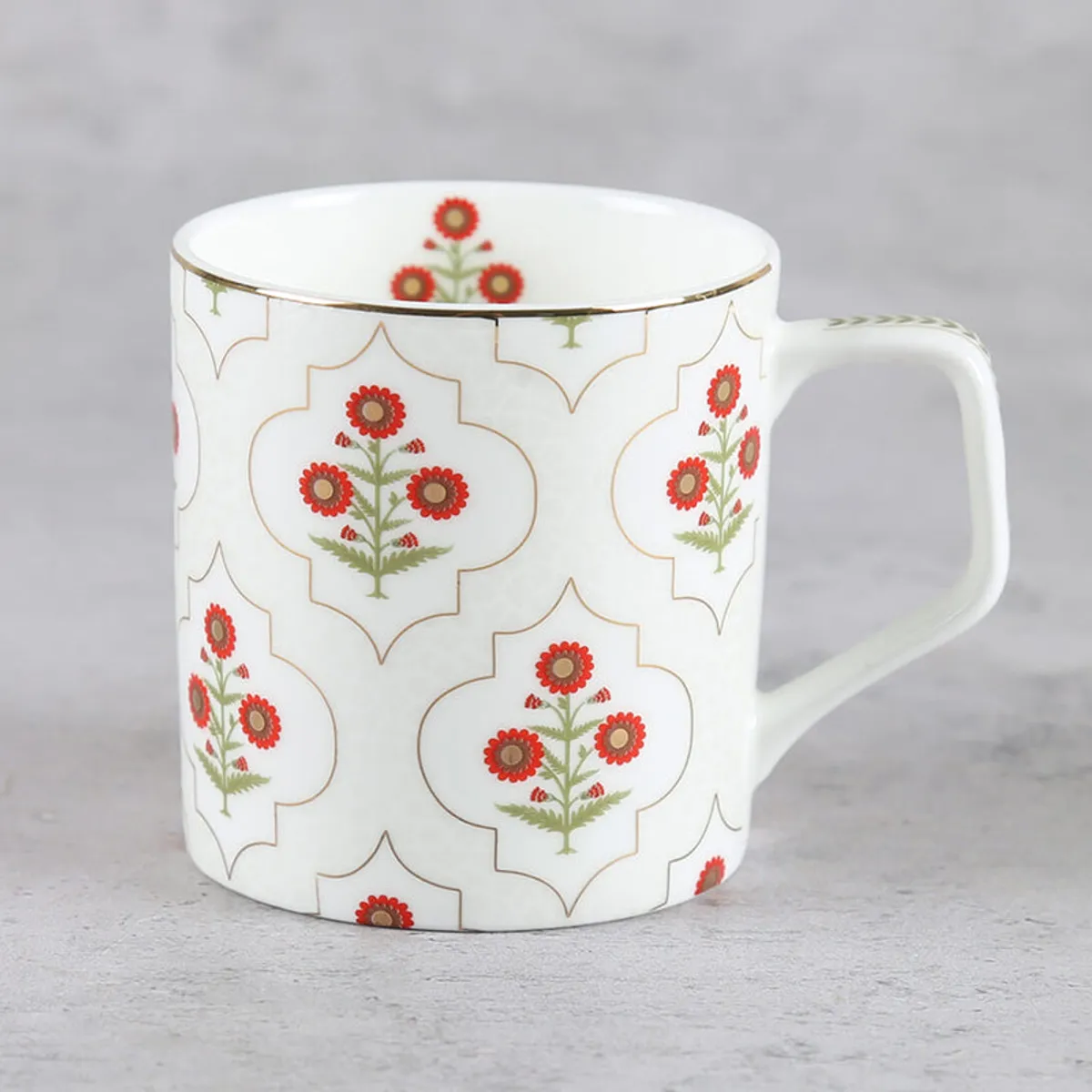 Close-up of an ivory tea cup with red floral motifs and gold rim detailing.