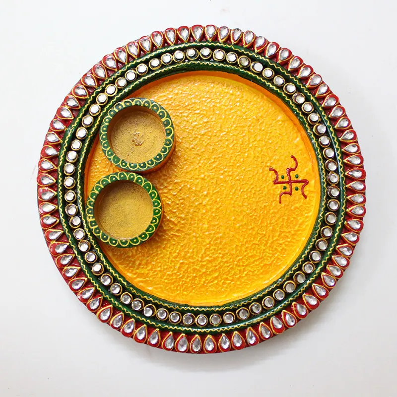 Top view of a yellow round pooja thali with two small bowls and a decorative rim