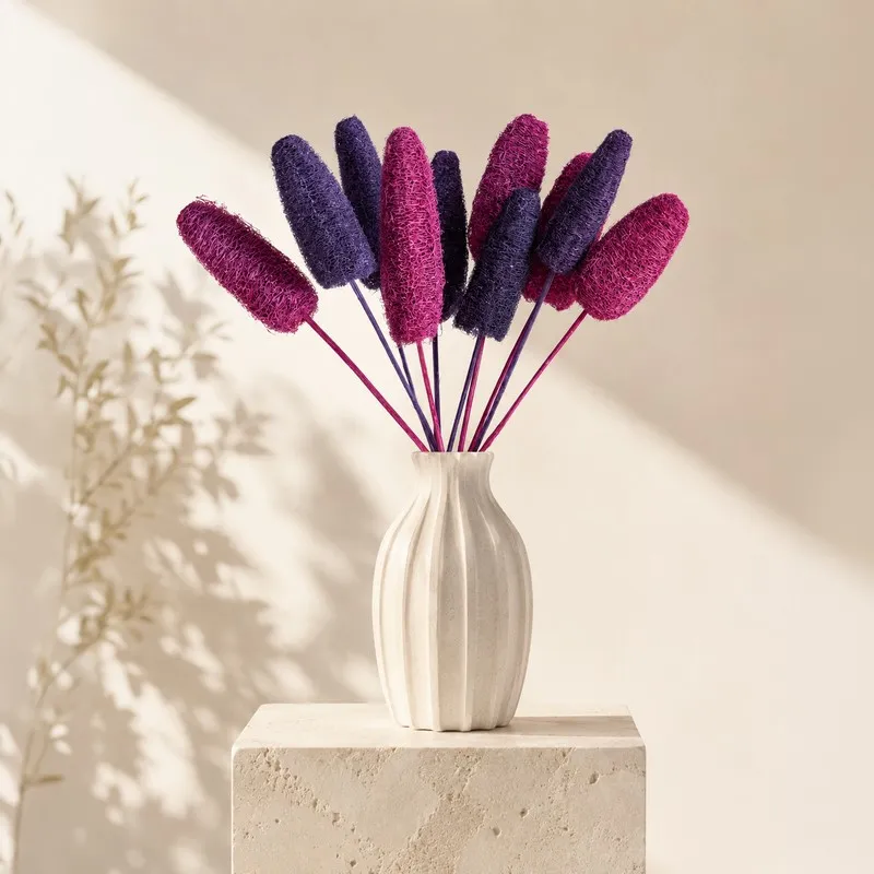 Pink and purple dried luffah stems displayed in a white ribbed vase