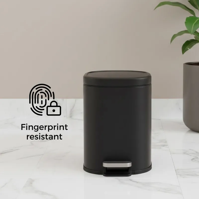 Black metal pedal dustbin with closed lid on a light floor