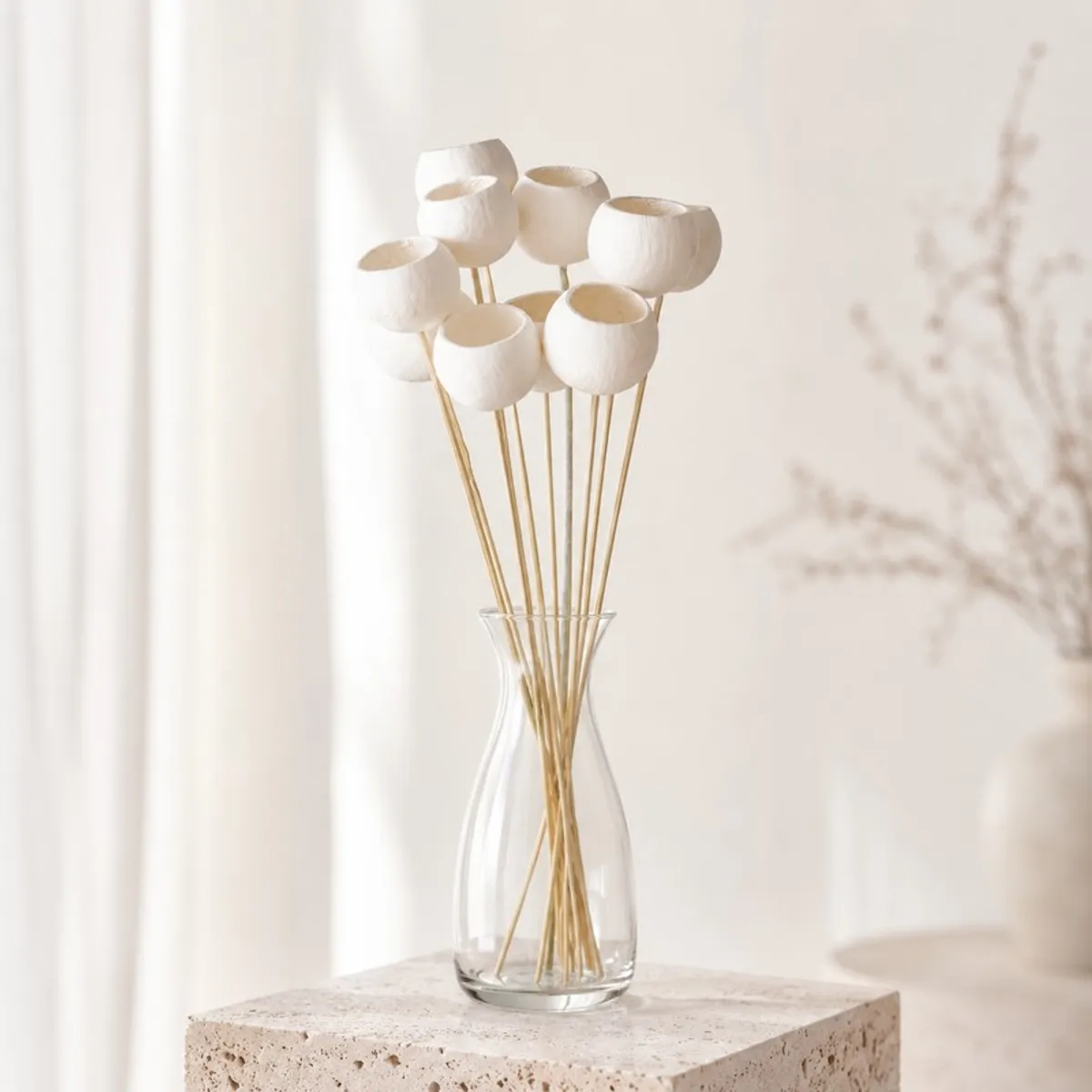 White bell cup dried stems arranged in a clear glass vase