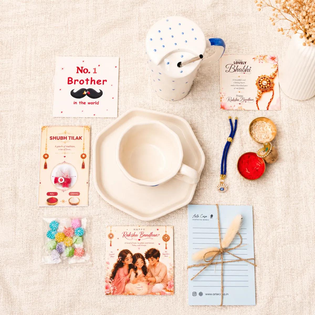 Top view of the Raksha Bandhan hamper contents arranged around a ceramic mug and sipper.