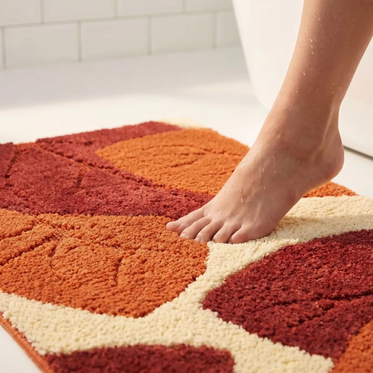Close-up of a foot on the plush rust and cream abstract bath mat