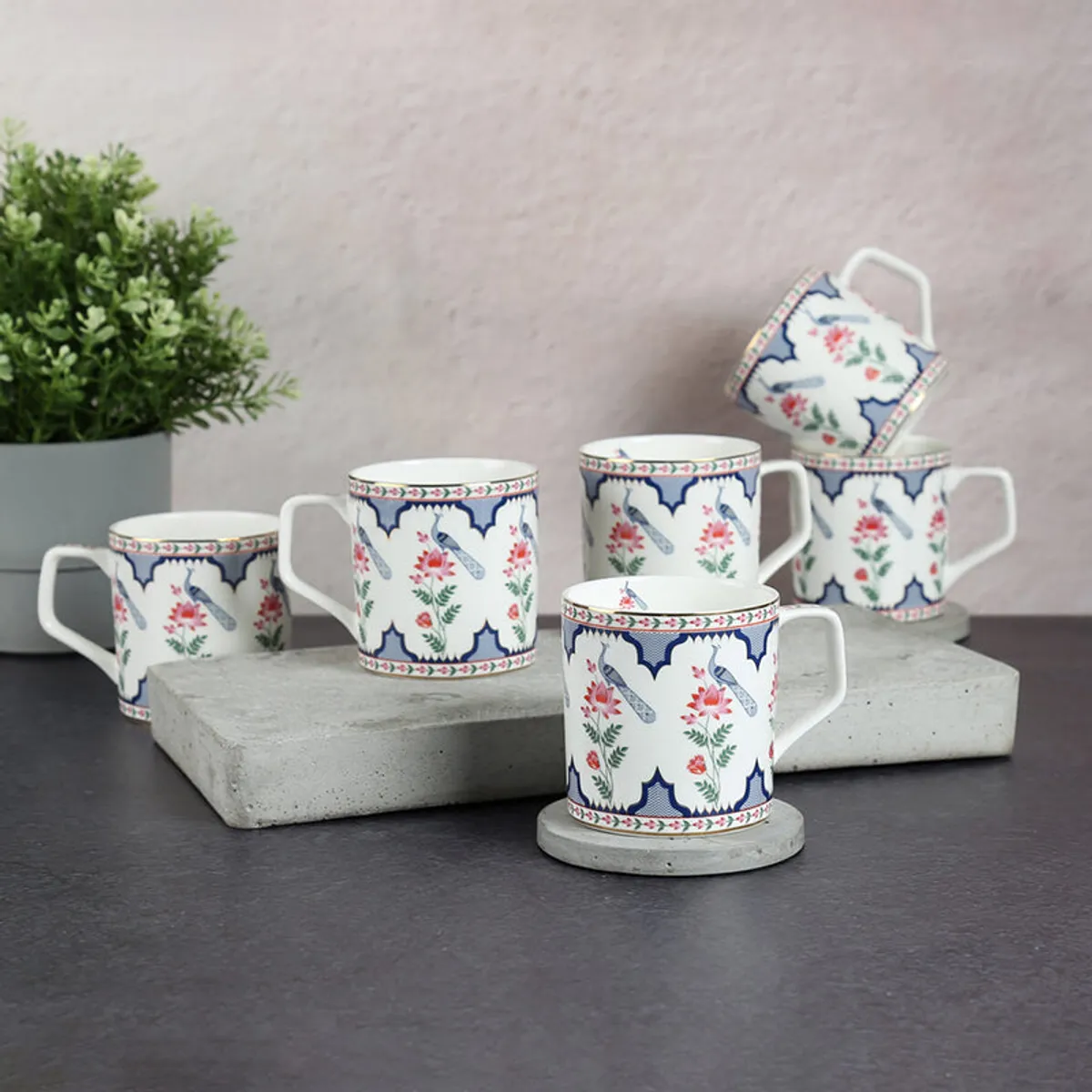 Six printed ivory tea cups arranged on display stands