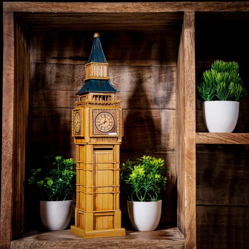 Tall clock tower iron showpiece displayed on a wooden shelf