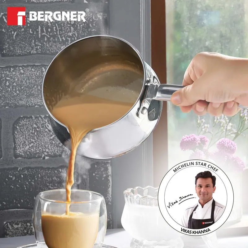 Silver saucepan being used to pour a warm beverage into a glass