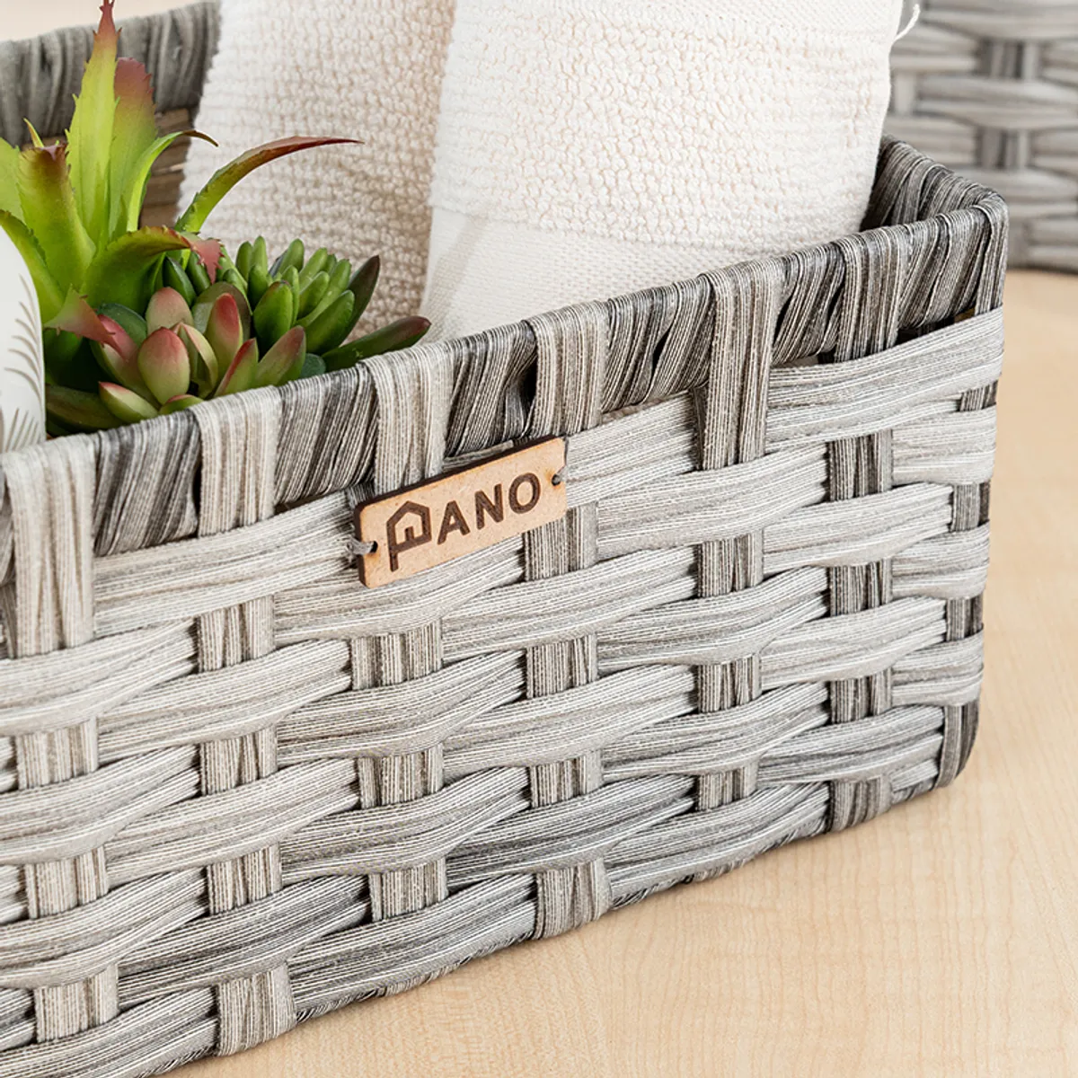 Close-up of a grey woven-look storage basket with toiletries and a plant inside