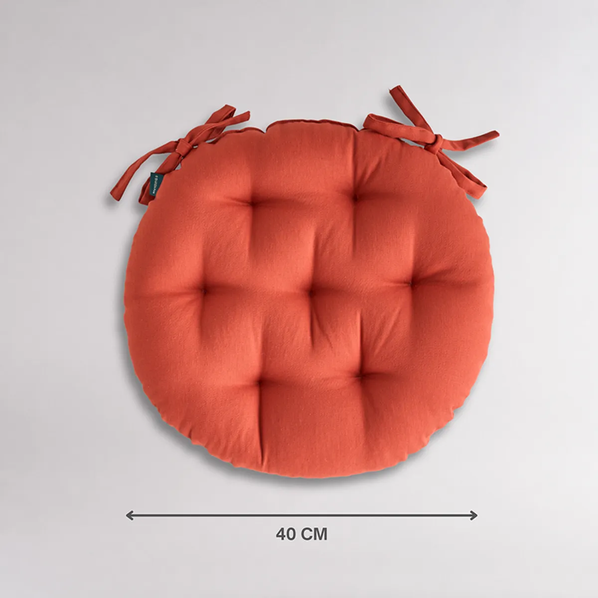 Top view of a round terracotta brown chair pad with tie-ups