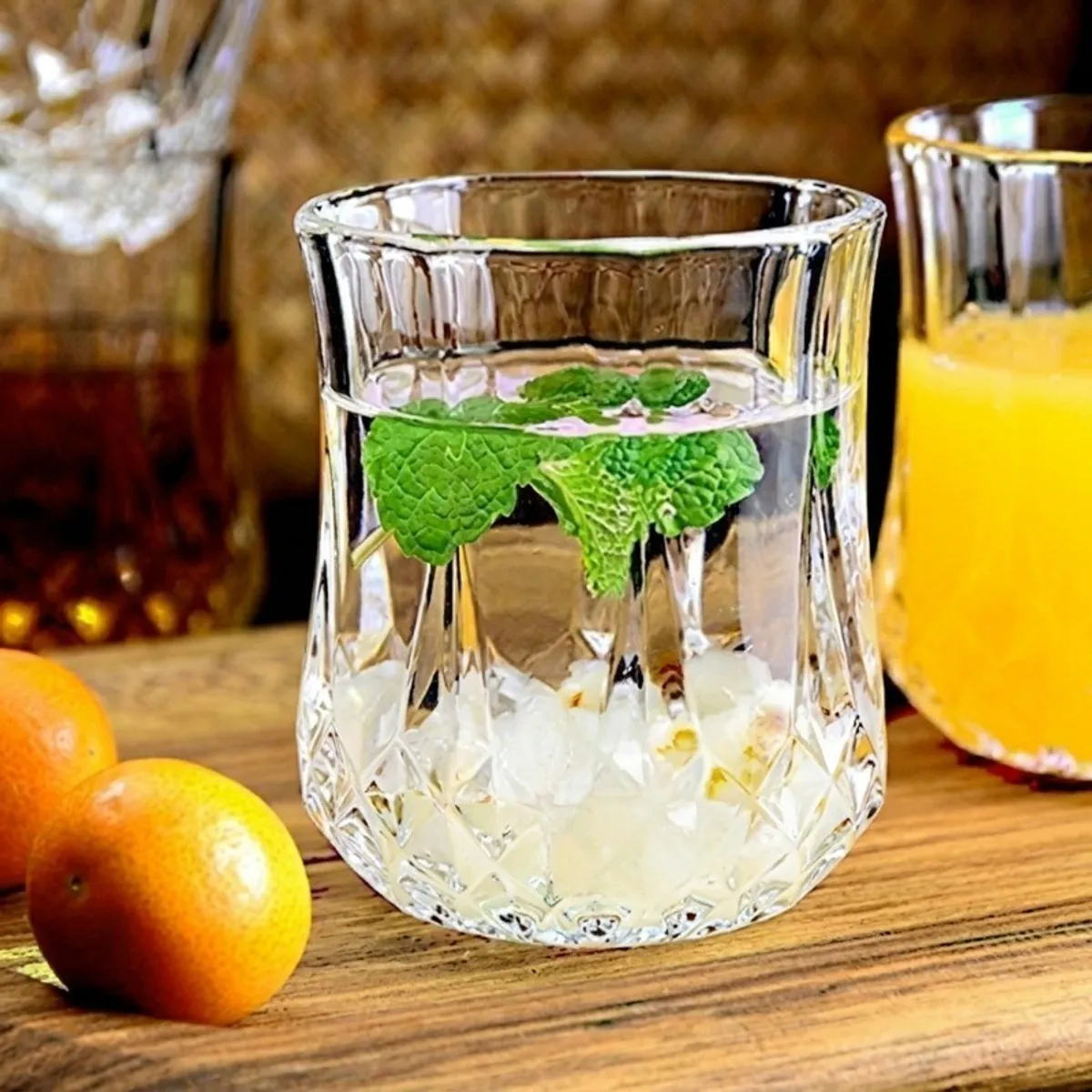 Clear textured glass filled with a mint and citrus drink on a wooden table