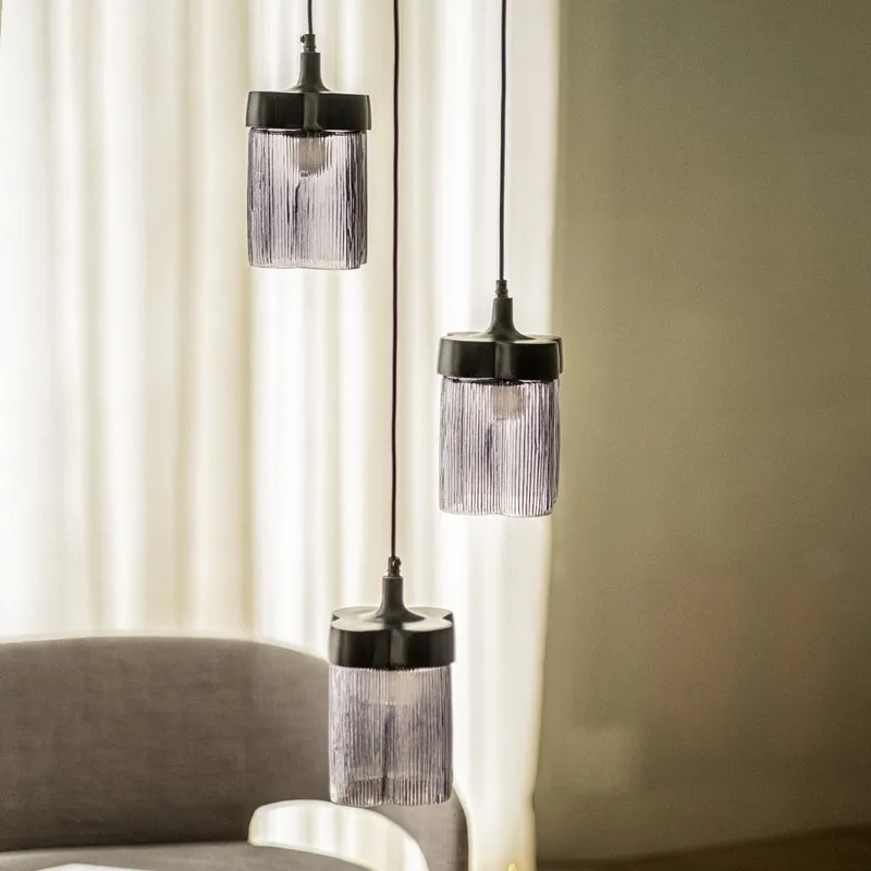 Three smoky cylindrical glass hanging lamps with black metal fittings