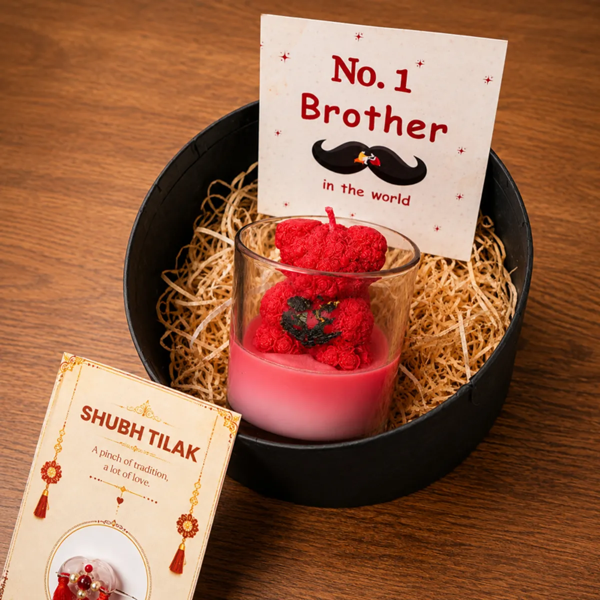 Rakhi hamper arranged in a black gift box with red teddy candle and cards