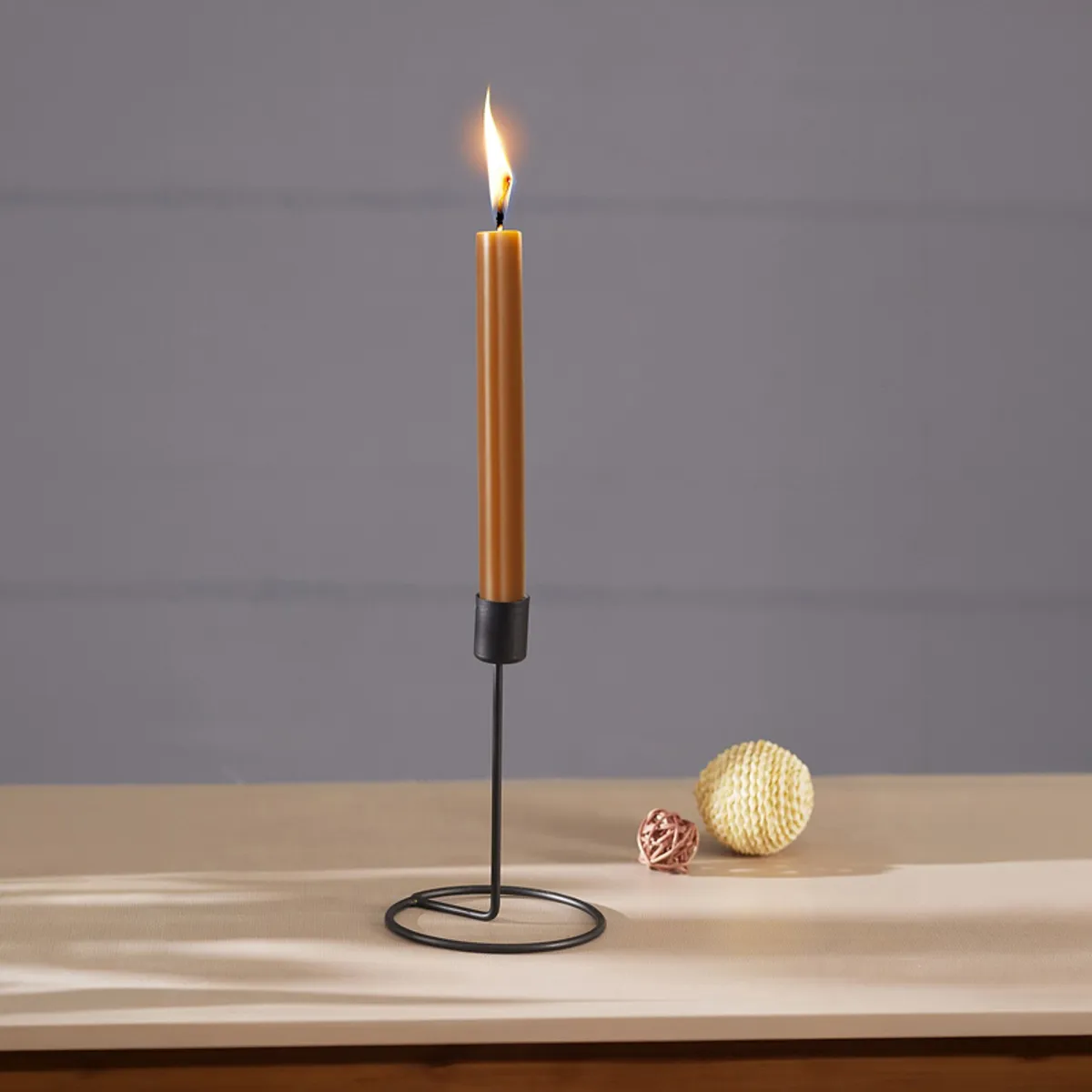 Black metal tealight holder with a lit candle on a tabletop