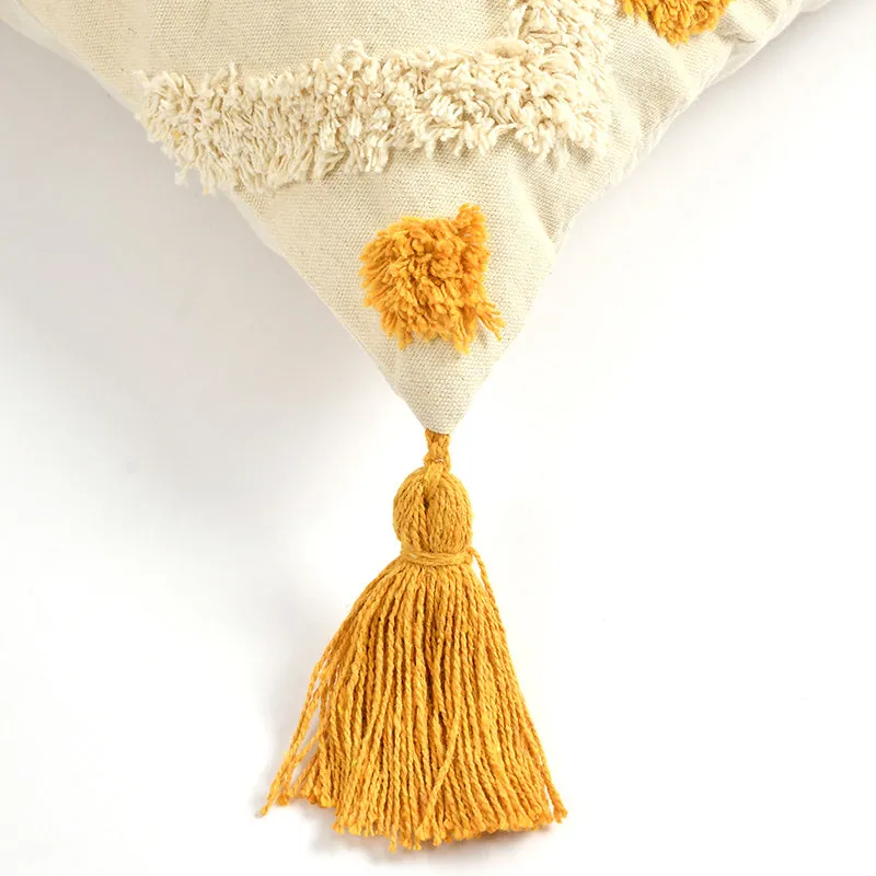 Close-up of cream tufted texture with a mustard pom-pom and tassel