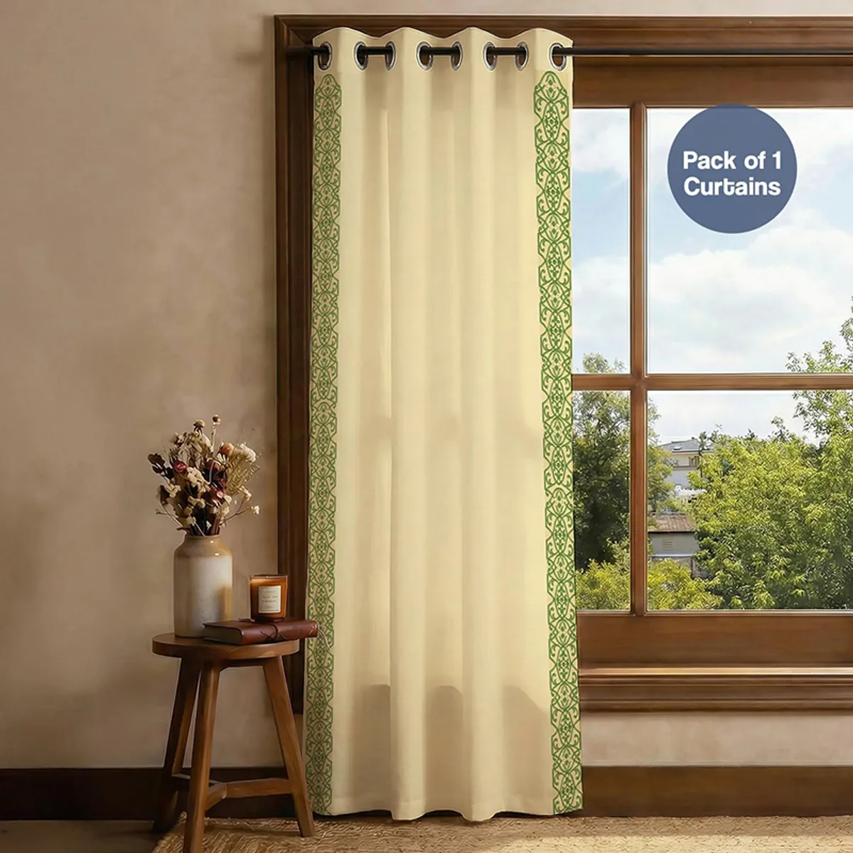 Single beige and green border curtain hanging over a bright window