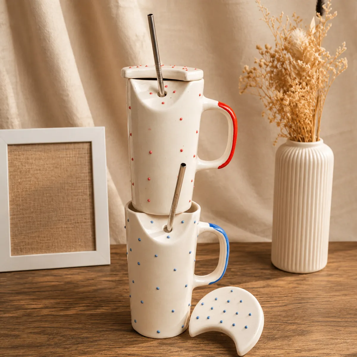Stacked blue and red ceramic sippers with round lids and metal straws