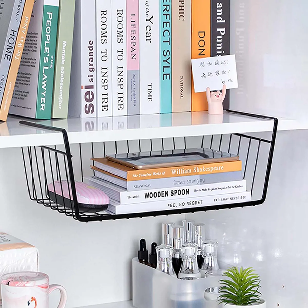 Black under-shelf metal rack holding books beneath a white bookshelf
