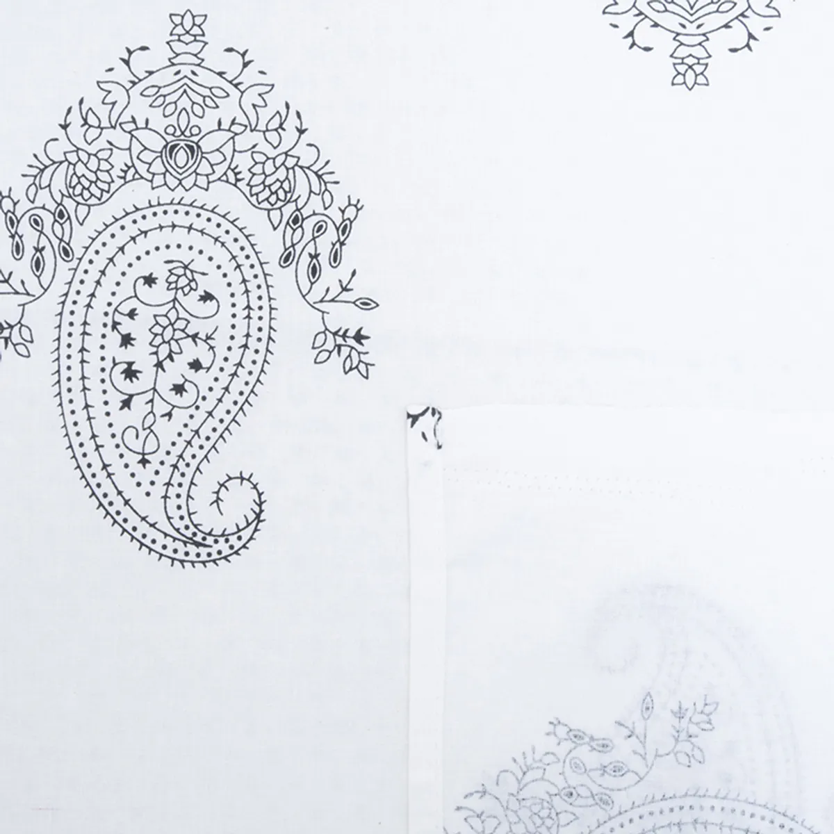 White bedsheet close-up with a large black paisley floral motif