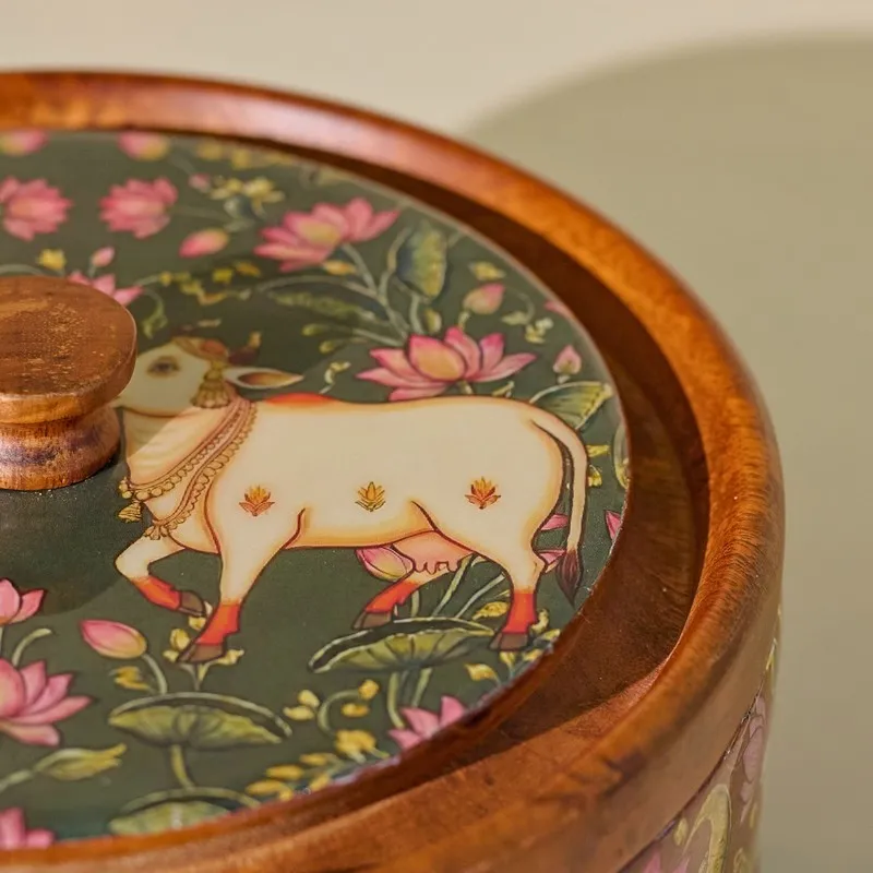 Close-up of glossy wooden lid with floral artwork and a figurative cow motif