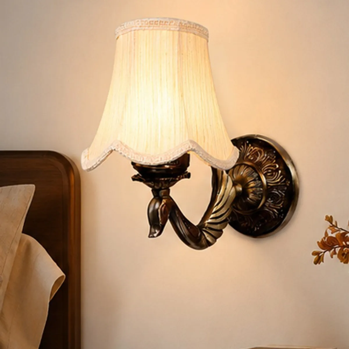 White cotton wall lamp with ornate metal base displayed beside a bedroom headboard