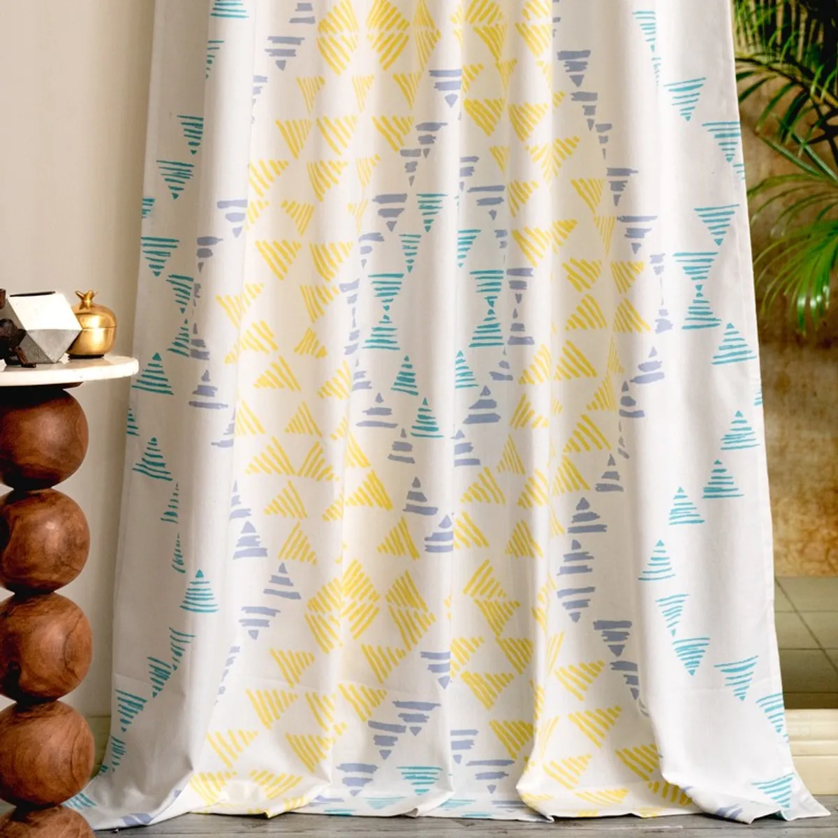 Full-length patterned curtain beside a plant and warm-toned decor