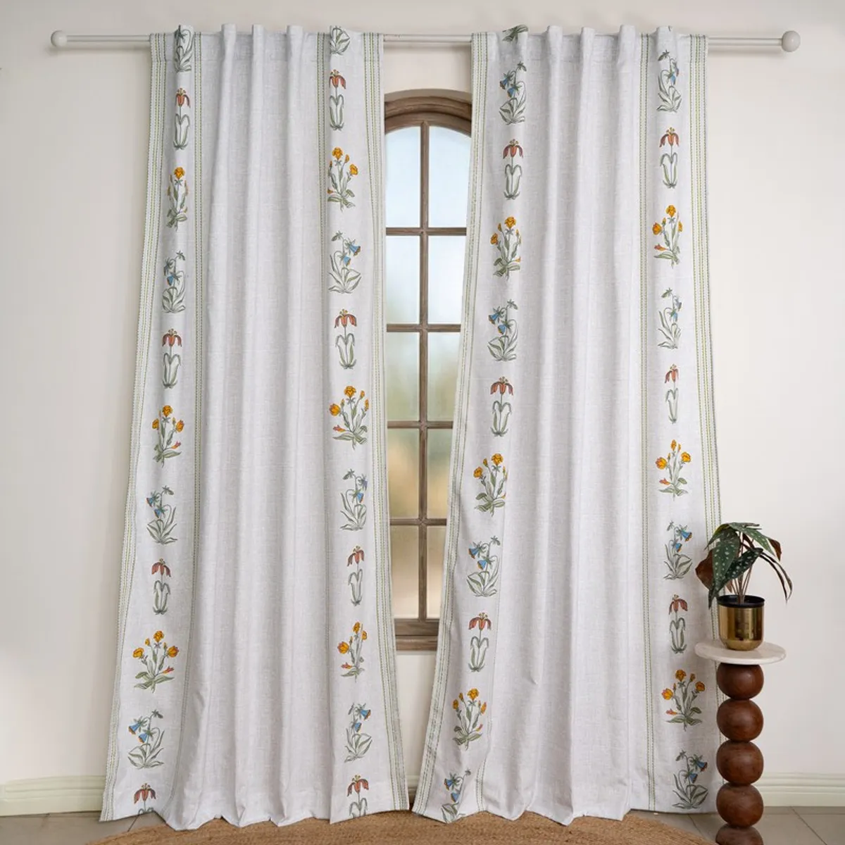 Pair of white floral curtains hanging from a rod around a window