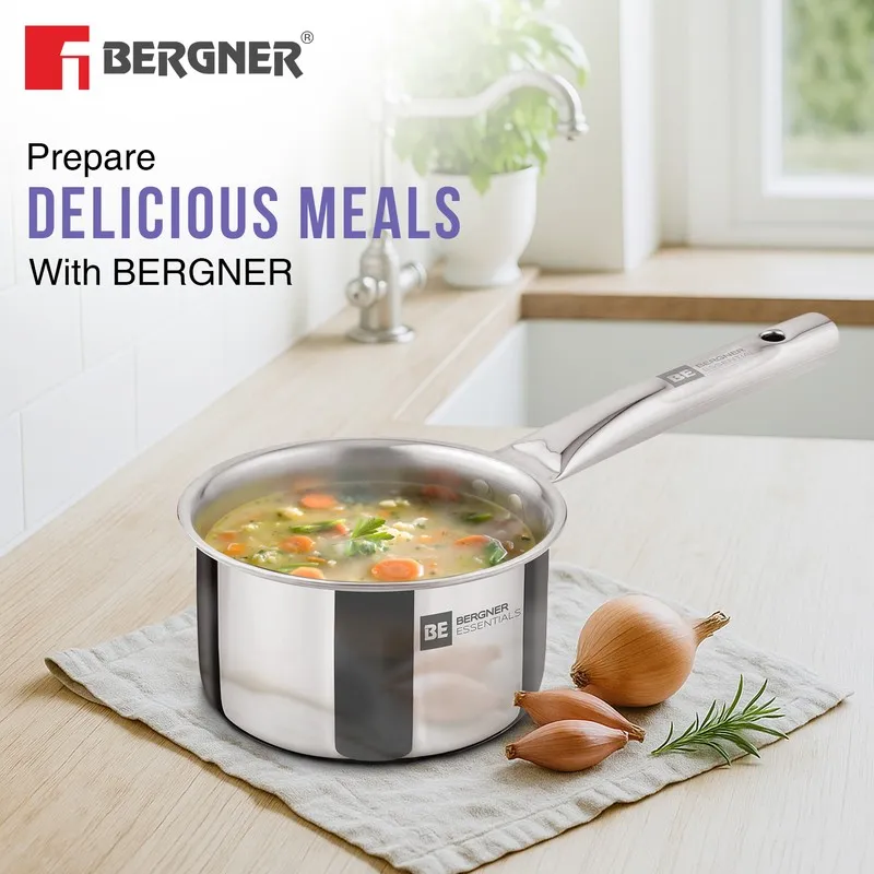 Silver saucepan with soup presented in a bright kitchen setting.