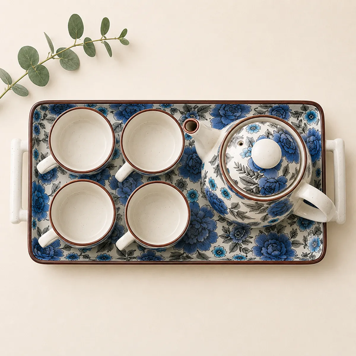 Top view of blue floral ceramic teapot, four cups and serving tray