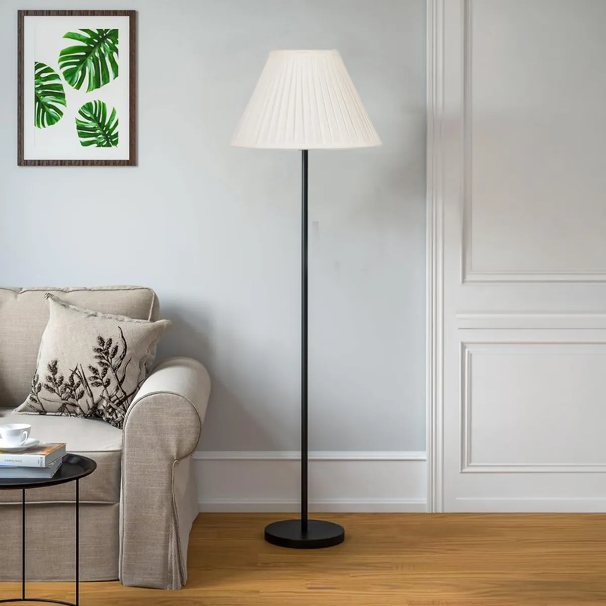 White pleated floor lamp styled beside a beige sofa in a bright living room