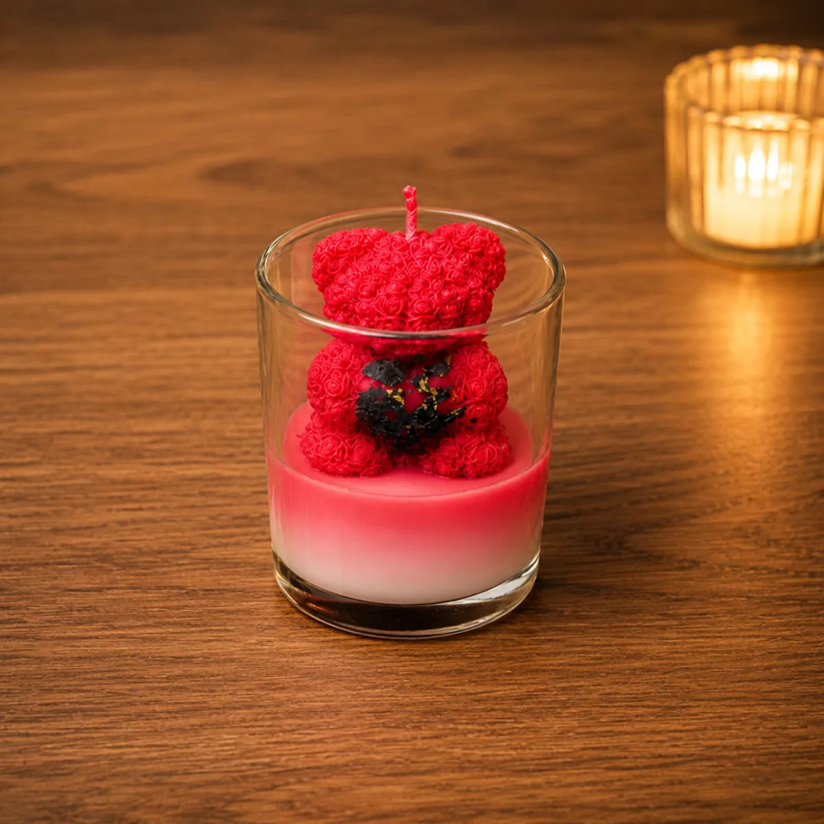 Red teddy scented candle in a clear glass holder on a wooden surface