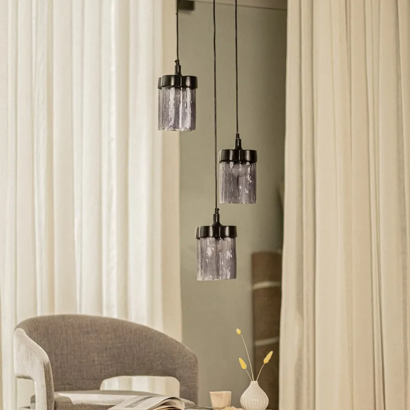 Cluster of three smoky glass ceiling lamps with black fittings against soft curtains