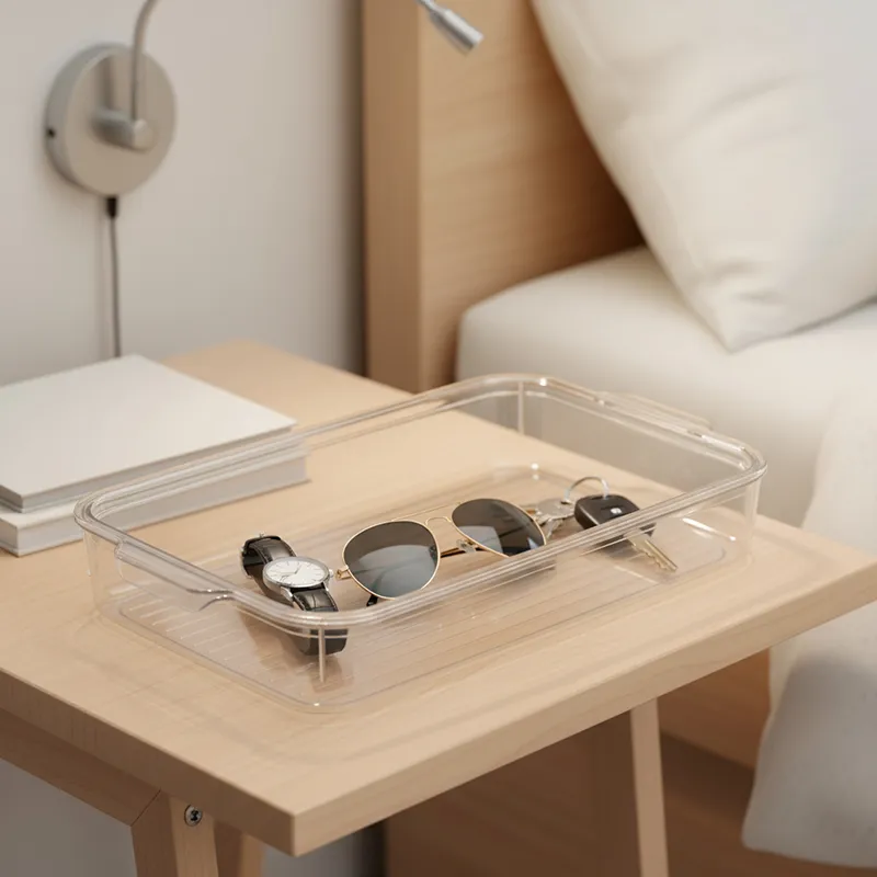 Clear organiser holding sunglasses, a watch and keys on a bedside table