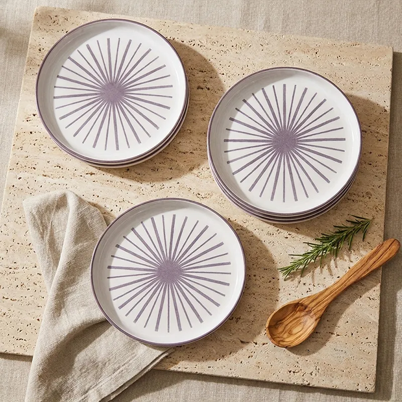 Top view of white plates with purple starburst design arranged in stacks
