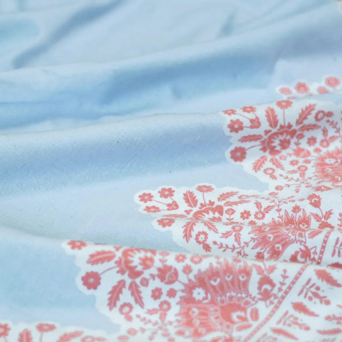 Close-up of light blue fabric with pink floral print