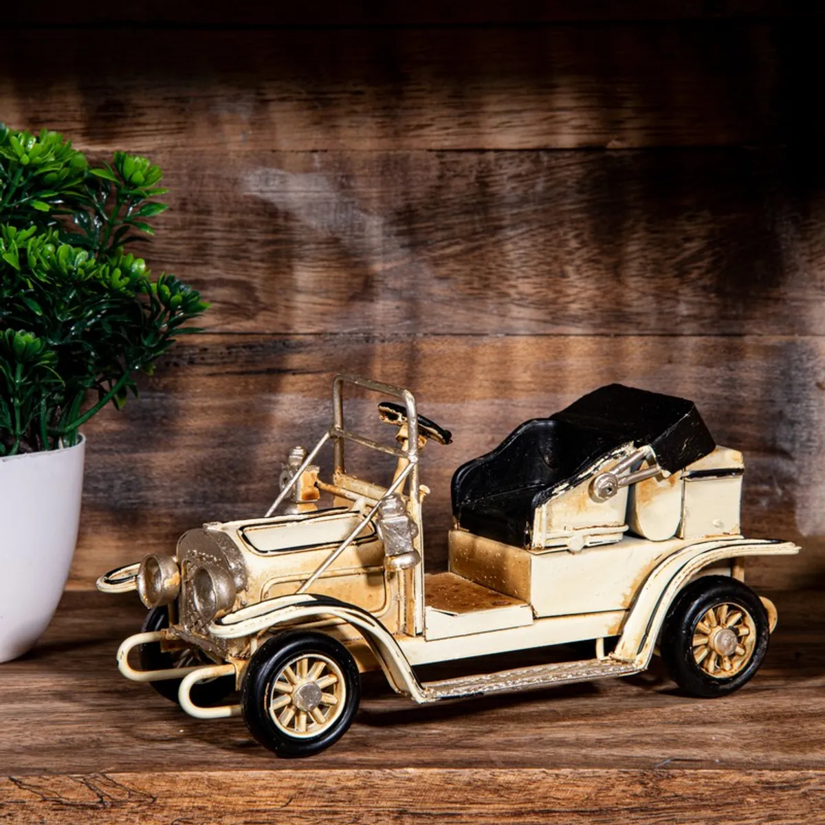 Side view of a vintage ivory and black car showpiece on a wooden surface