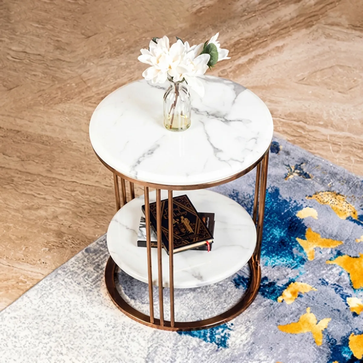 Round marble side table with books on the lower shelf beside a colourful rug
