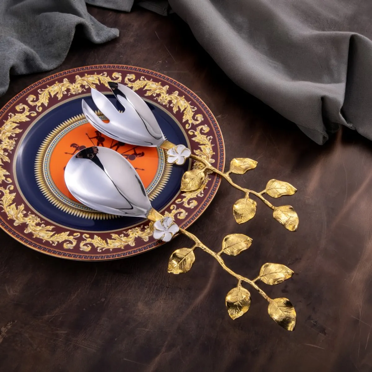 Leaf salad servers styled on an ornate dinner plate with a grey cloth