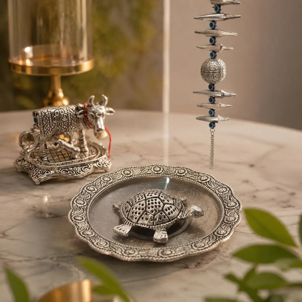Brown and silver metal cow idol, turtle plate and hanging décor on a tabletop