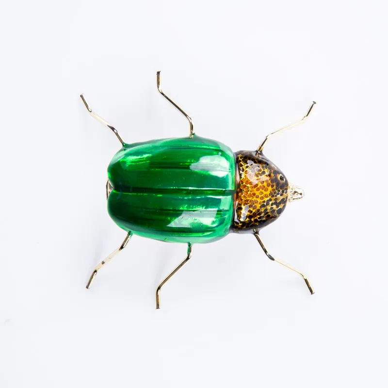 Top view of green and gold dung beetle figurine